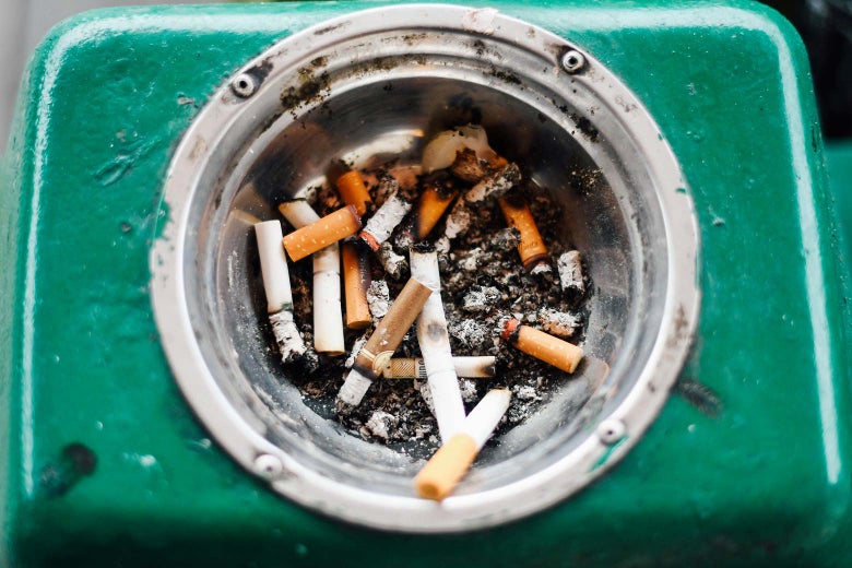 Used cigarette butts in a dirty ashtray.